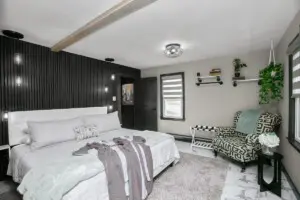Modern cottage retreat bedroom with black accent wall, white tufted headboard, and patterned armchair at Copper Top Ridge