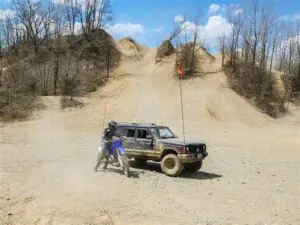 Jeep and dirt bike with dune flags at Bundy Hill Off-Road Park during off-roading in Southwest Michigan