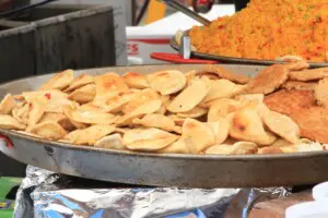 A steaming plate of pierogi served at Pierogi Fest, surrounded by traditional toppings like sour cream and onions.