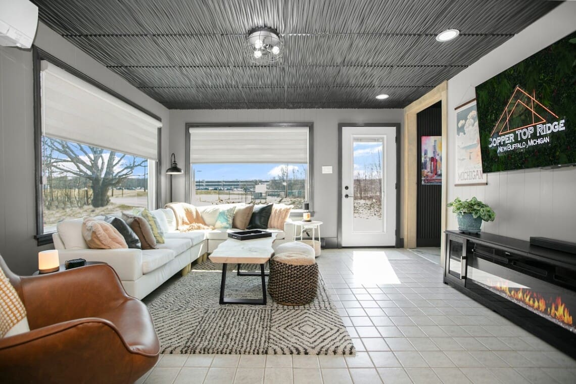 Luxury vacation rental living room at Copper Top Ridge in New Buffalo, MI with fireplace, panoramic windows, and cozy modern furnishings