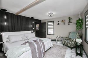 Modern cottage retreat bedroom with black accent wall, white tufted headboard, and patterned armchair at Copper Top Ridge