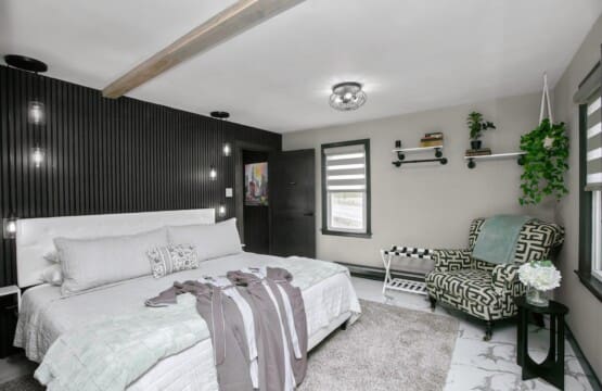 Modern cottage retreat bedroom with black accent wall, white tufted headboard, and patterned armchair at Copper Top Ridge
