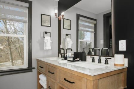 Modern double vanity bathroom with black fixtures and wood cabinetry at Copper Top Ridge