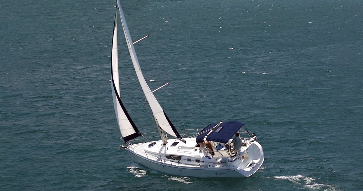New Buffalo Sailing Excursions | Things to Do in Southwest Michigan: Private sailboat gliding on Lake Michigan at sunset with passengers on deck.