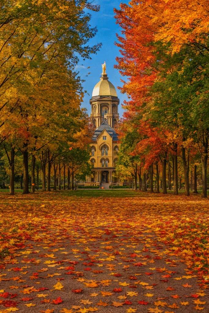 Notre Dame gameday itinerary begins at the Golden Dome with vibrant fall foliage and leaves across the ground