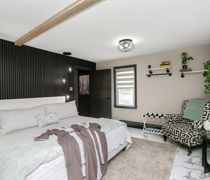 Luxury Vacation Rental in New Buffalo featuring a modern cottage-style bedroom with king bed, designer chair, and elegant decor.
